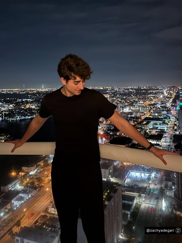 Zach Yadegari Net Worth, Cal AI Founder Story, Vision & Growth 2 Zach Yadegari, founder of Cal AI, stands on a high-rise balcony overlooking a glowing city skyline at night.