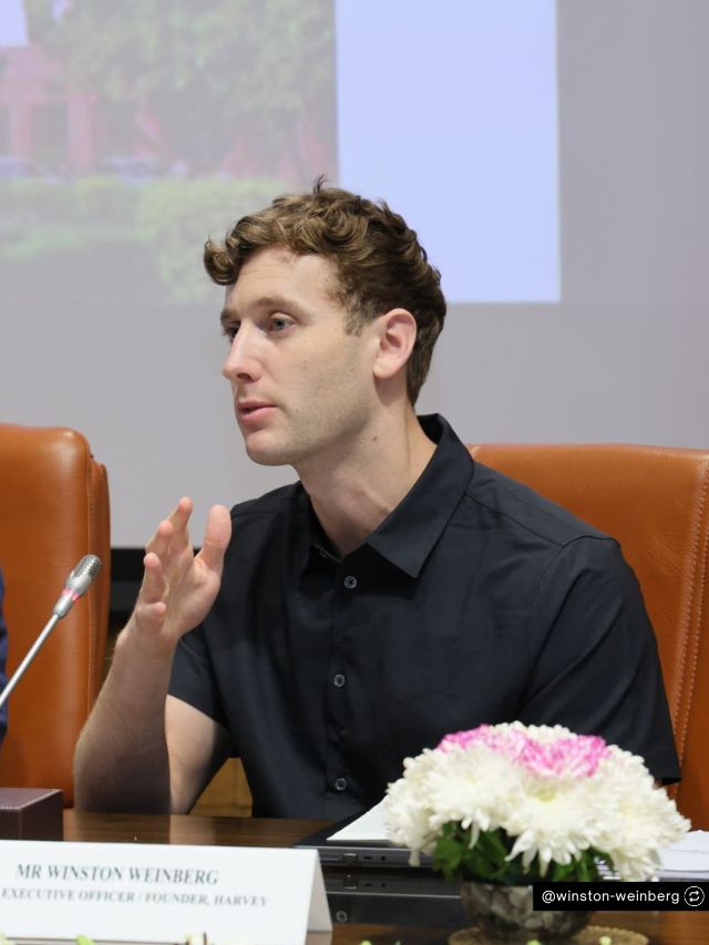Harvey Co-Founder Winston Weinberg Net Worth, Entrepreneur Journey & Success 2
Winston Weinberg, co-founder of Harvey, speaks during a panel while wearing a black polo, with a nameplate visible in front of him.