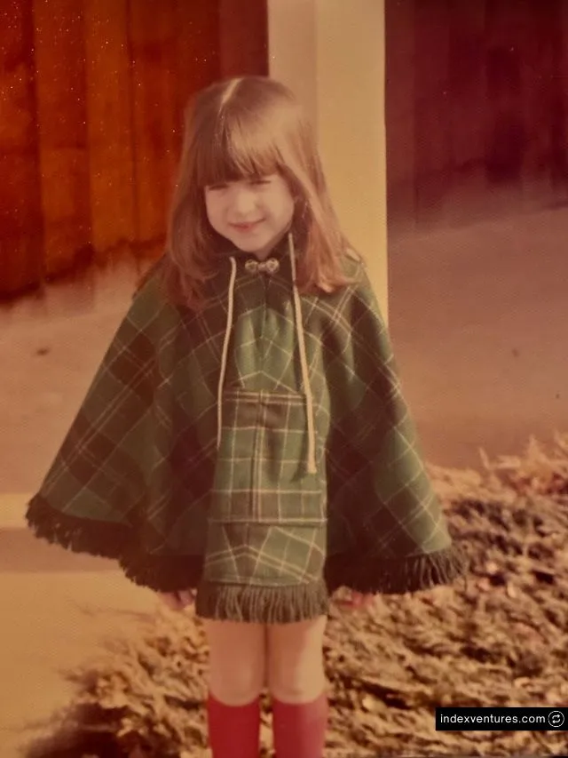 Daydream Founder Julie Bornstein Net Worth and AI Business Journey 2 A vintage childhood photo of a young Julie Bornstein smiling in a green plaid fringed poncho and bright red knee-high socks.